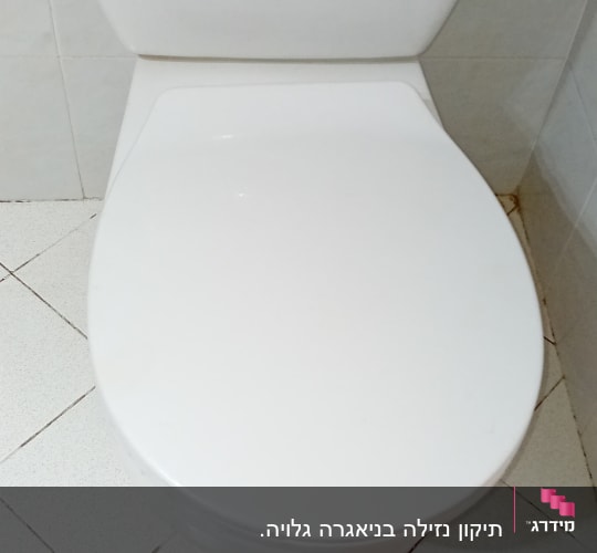 אסלה לבנה עם מכסה סגור בחדר אמבטיה